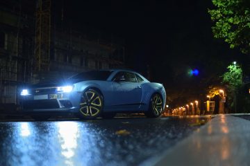 Blue vehicle at night with lights parked on wet road.